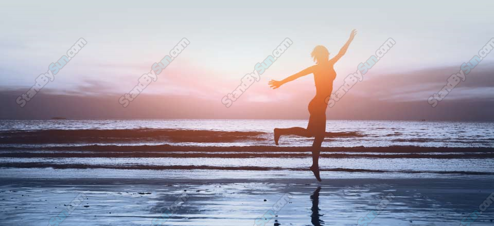 woman dancing on beach at sunset